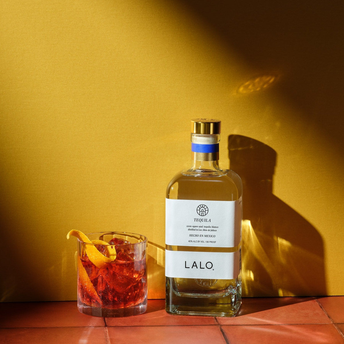 LALO Tequila Blanco beside a Negroni cocktail with an orange twist