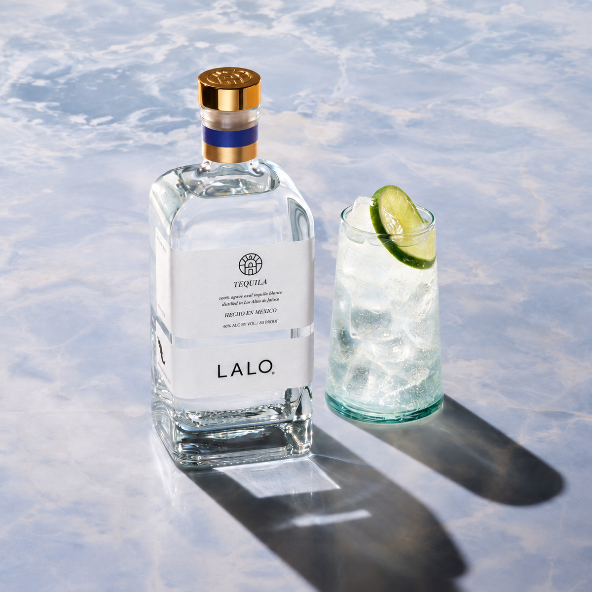 LALO Tequila Blanco bottle beside a Ranch Water cocktail garnished with lime